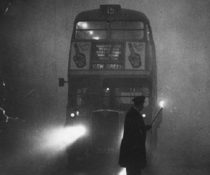 A man guiding a London bus through thick fog with a flaming torch.   (Photo by Monty Fresco/Getty Images)