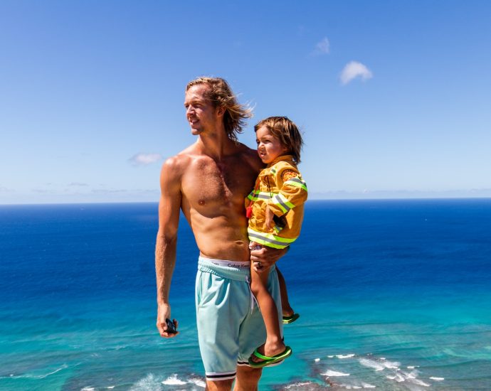 a man and a child standing on a cliff overlooking the ocean