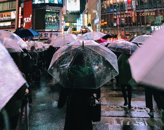 people with umbrellas walking near buildings during night