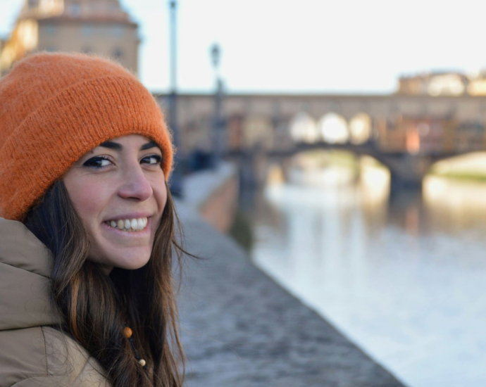 a woman wearing a orange knitted hat next to a river