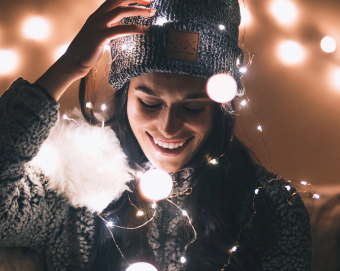 woman in black knit cap holding string lights