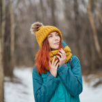 woman in blue jacket and brown knit cap standing on snow covered ground during daytime