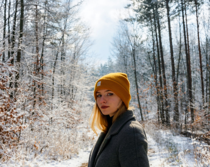 a woman in a yellow hat is standing in the snow