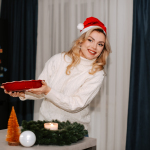 a woman in a santa hat is holding a cake