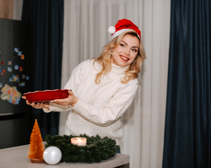 a woman in a santa hat is holding a cake