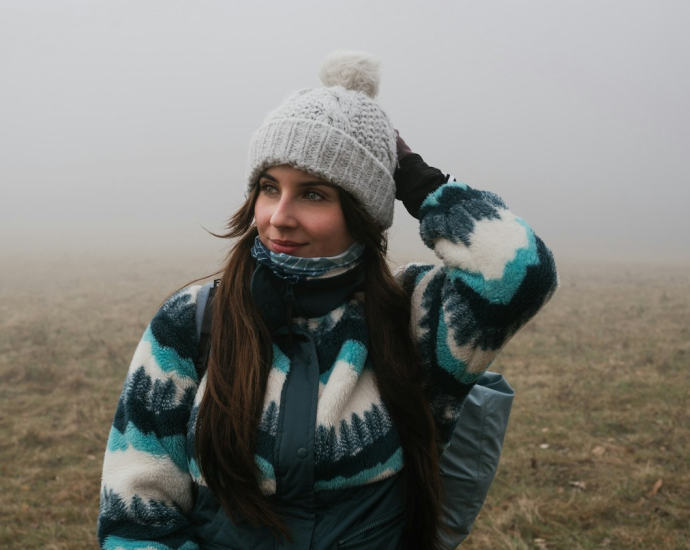 a woman wearing a hat and scarf in a foggy field