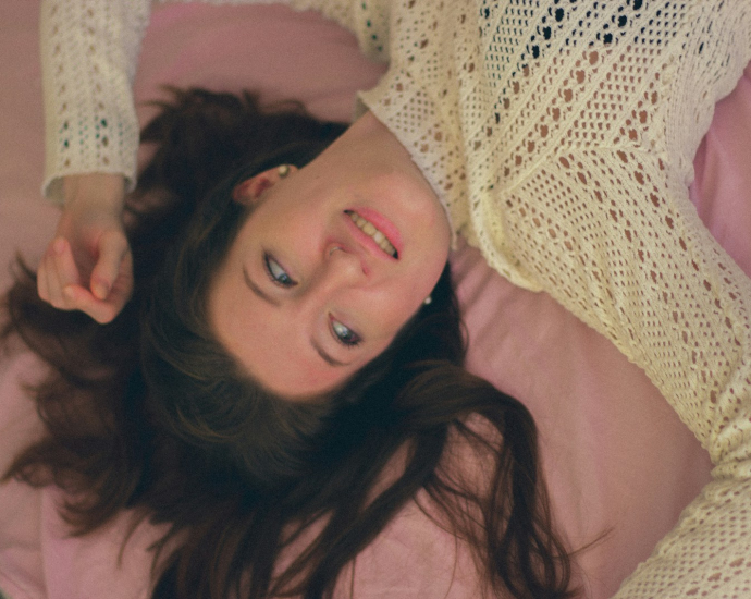 a woman laying on a bed with a pink blanket