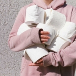 Woman in Pink Long Sleeve Hoodie Carrying Tissue Rolls