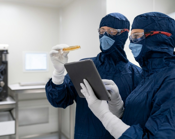 a couple of people wearing masks and gloves and holding a tablet