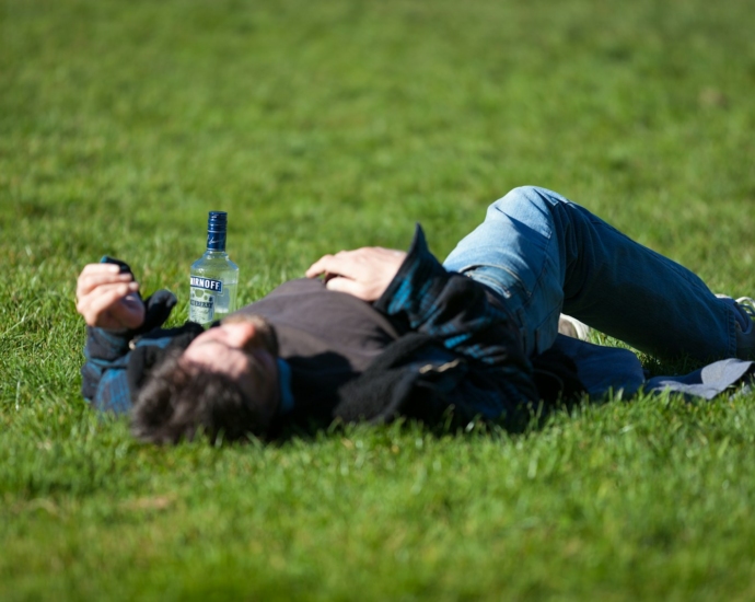 a man laying in the grass with a bottle of beer