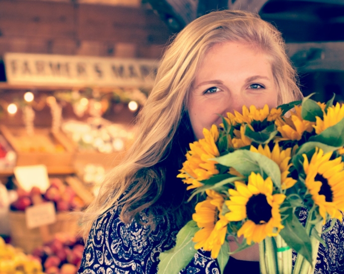 woman in blue and white floral top holding sunflower buoquet