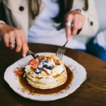 Person Eating Pancakes with Fresh Fruits