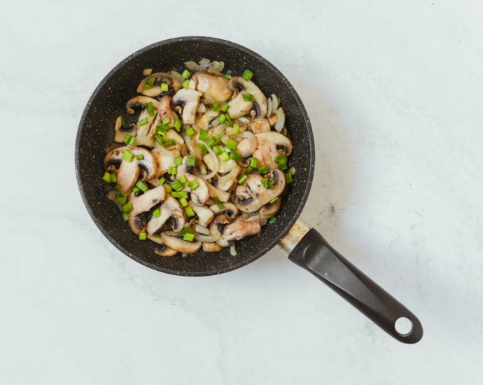 Champignon Muchrooms and Spring Onions in a Frying Pan 