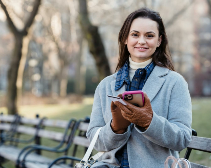 Smiling woman using smartphone on spring city park