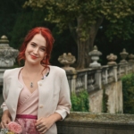 a woman with red hair is standing on a bridge
