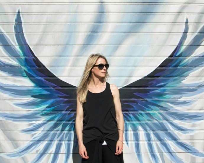 woman taking photo near wings painted wall