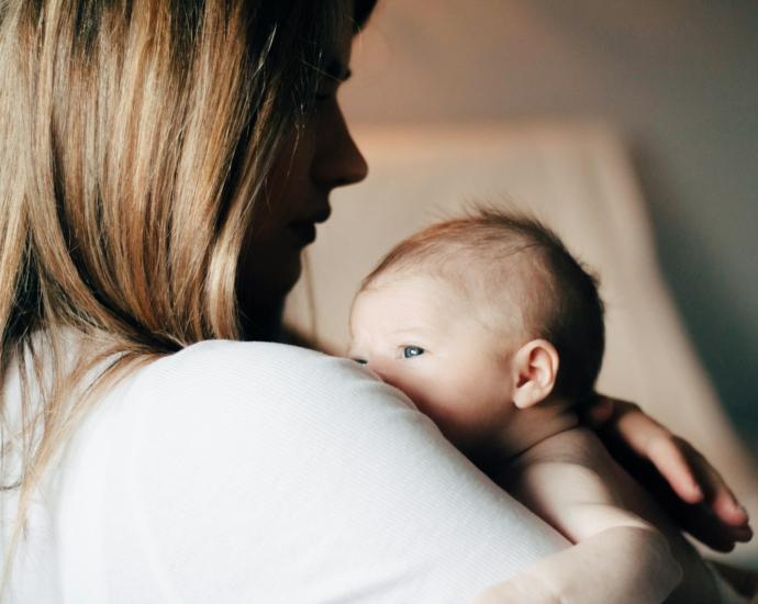 woman in white shirt carrying baby