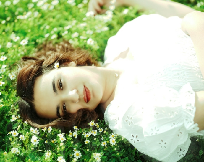 a woman in a white dress laying in a field of flowers