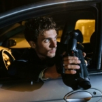 Man Sitting in a Car at Night, Holding a Camcorder and Looking Back through the Window