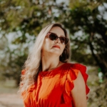 A woman in sunglasses and red dress standing on a path