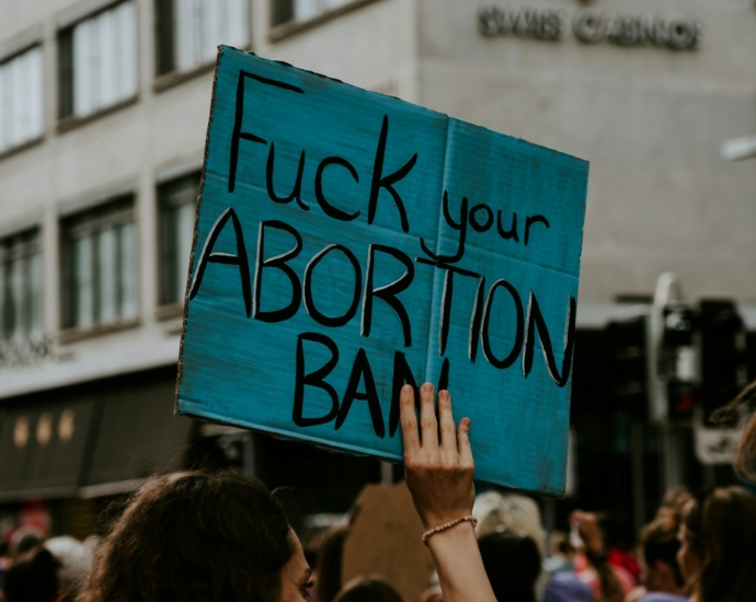 person holding fuck your abortion ban printed banner