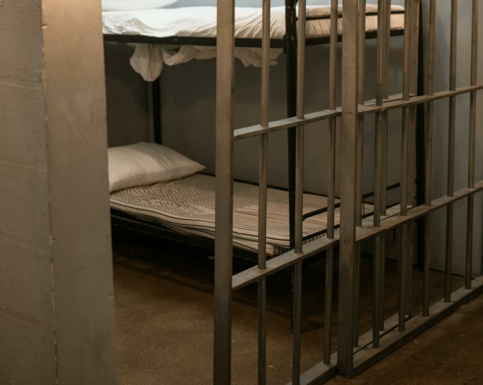 A Bunk Bed With Striped Linen Behind Bars