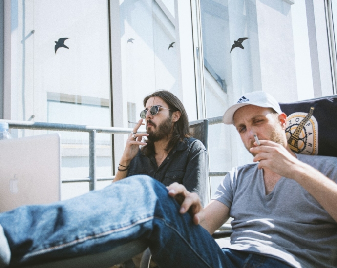 two mens doing smoke while sitting inside building at daytime
