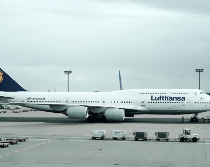 white and black Lufthansa airliner near vehicles