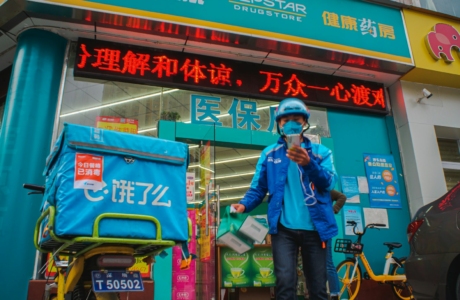 man in blue jacket and blue denim jeans standing beside green and red kanji text store