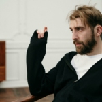 Man in Black Sweater Sitting on Brown Wooden Chair