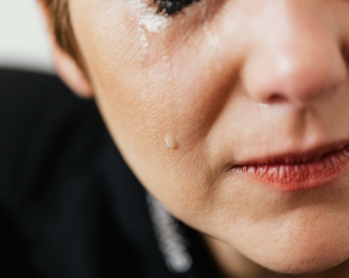 Closeup of crop anonymous sad adult female with makeup crying because of emotional problems