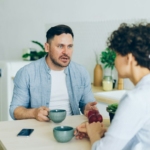 a man sitting at a table talking to a woman