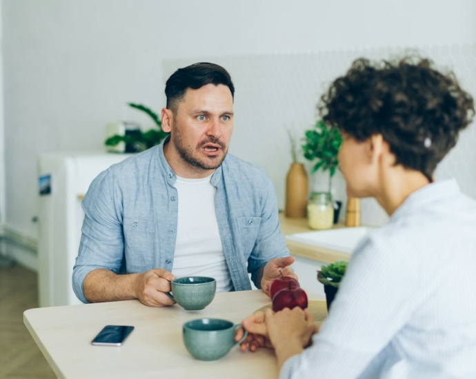 a man sitting at a table talking to a woman