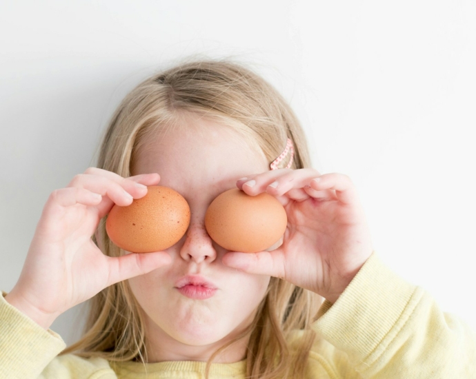 girl holding two eggs while putting it on her eyes