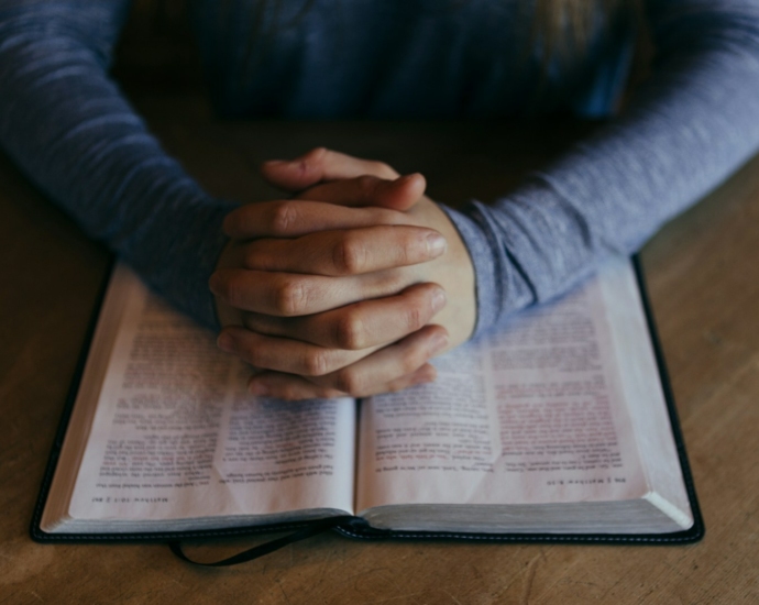 man holding his hands on open book