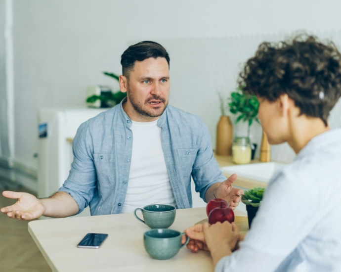 a man sitting at a table talking to a woman