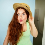 woman holding brown straw hat