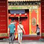 three people walking toward red building