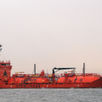 a large red boat floating on top of a body of water