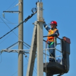 a man standing on top of a metal pole next to power lines