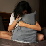 A woman sitting on a bed holding a pillow