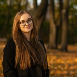 a woman wearing glasses standing in a park