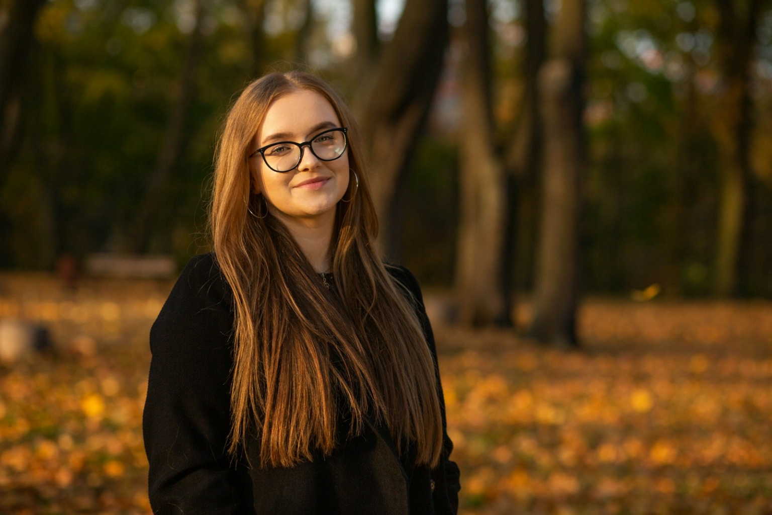 a woman wearing glasses standing in a park