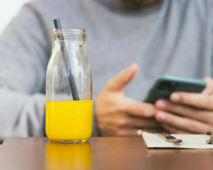 a person holding a phone and a glass of liquid