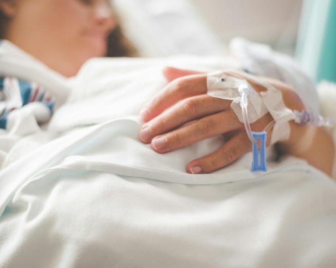 a woman laying in a hospital bed with an iv in her hand