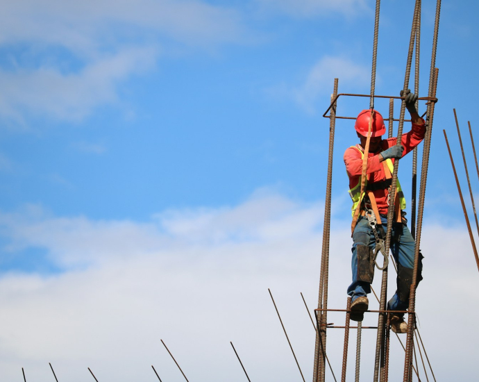 man wearing red hard hat hanged on brown rebar bar