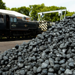 a train traveling past a pile of coal