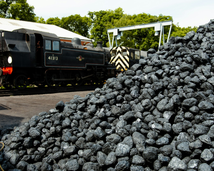 a train traveling past a pile of coal