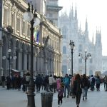 A crowd of people walking down a street next to tall buildings