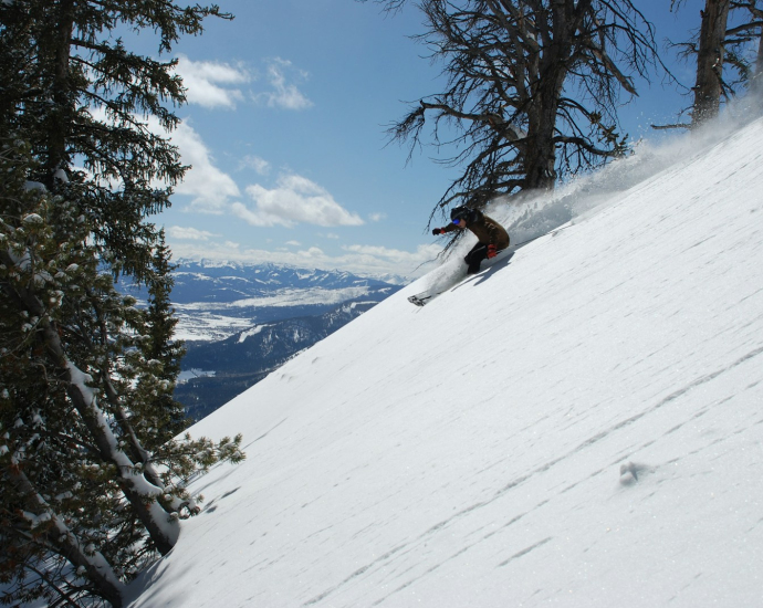 person sliding on snow-covered downhill with snowboard during daytime